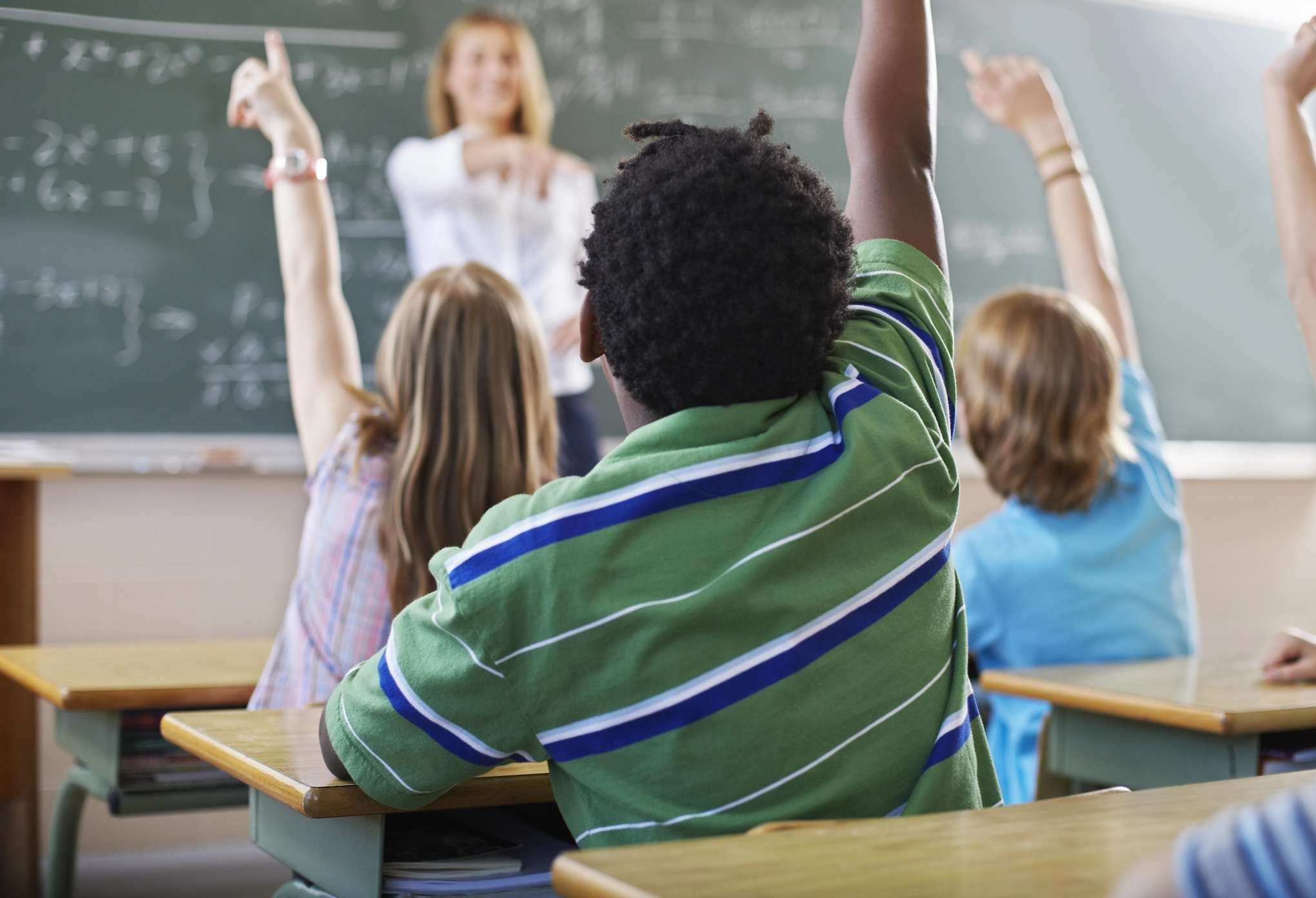 Kids in a classroom, raising their hand
