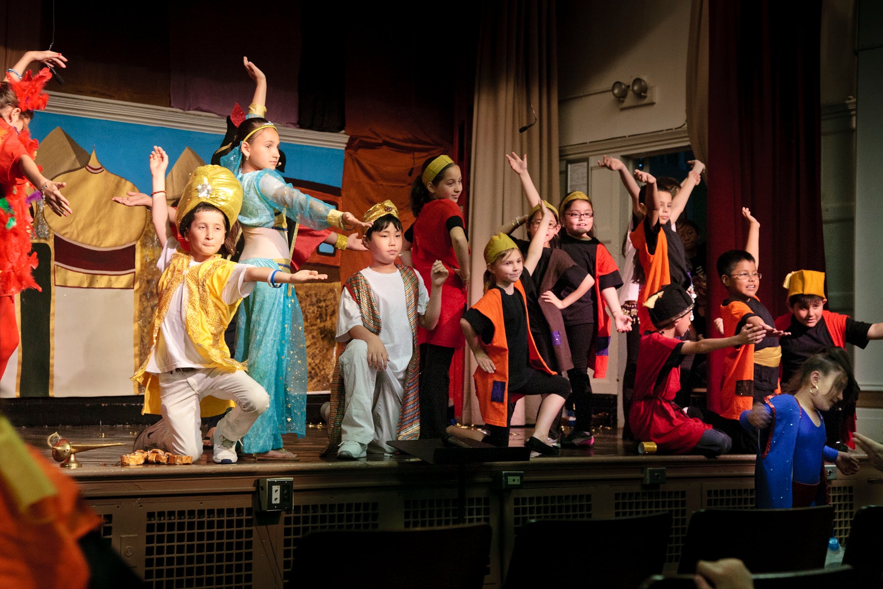 Children on stage strike a pose at the end of their play performance.