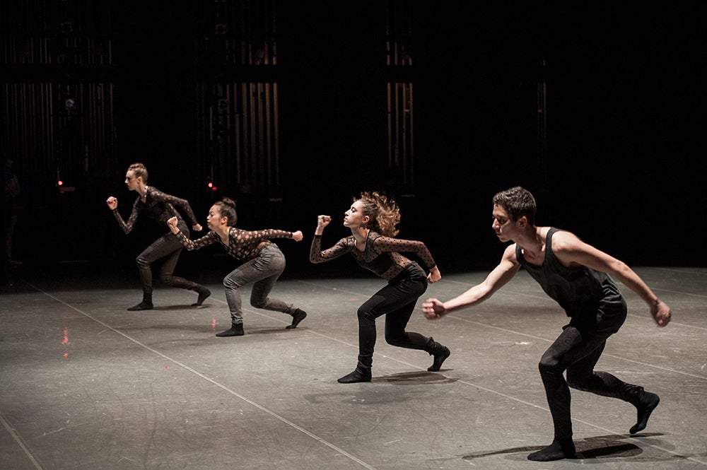 Four dancers in motion on stage.