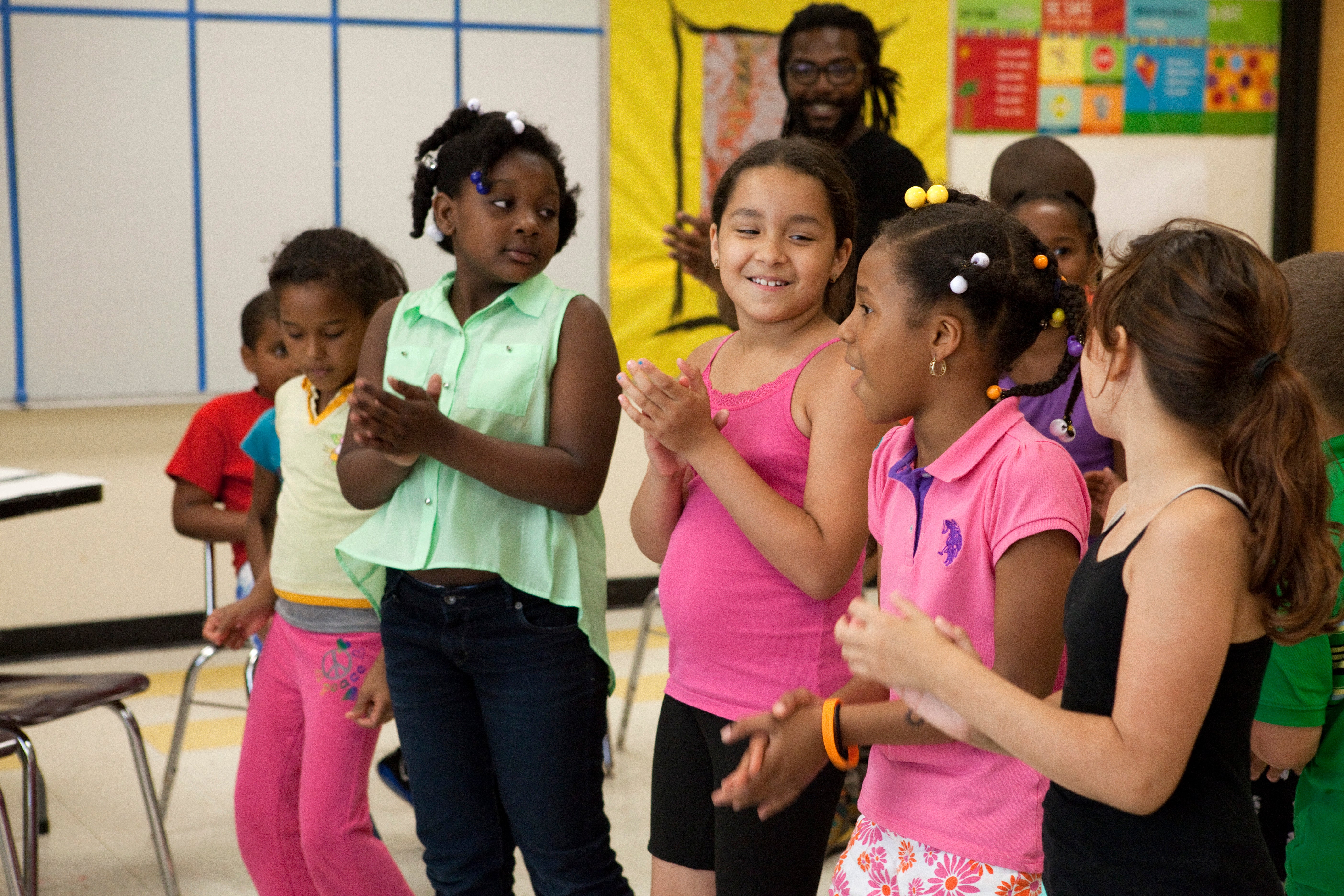 Young girls sing and clap in a circle during an afterschool program.