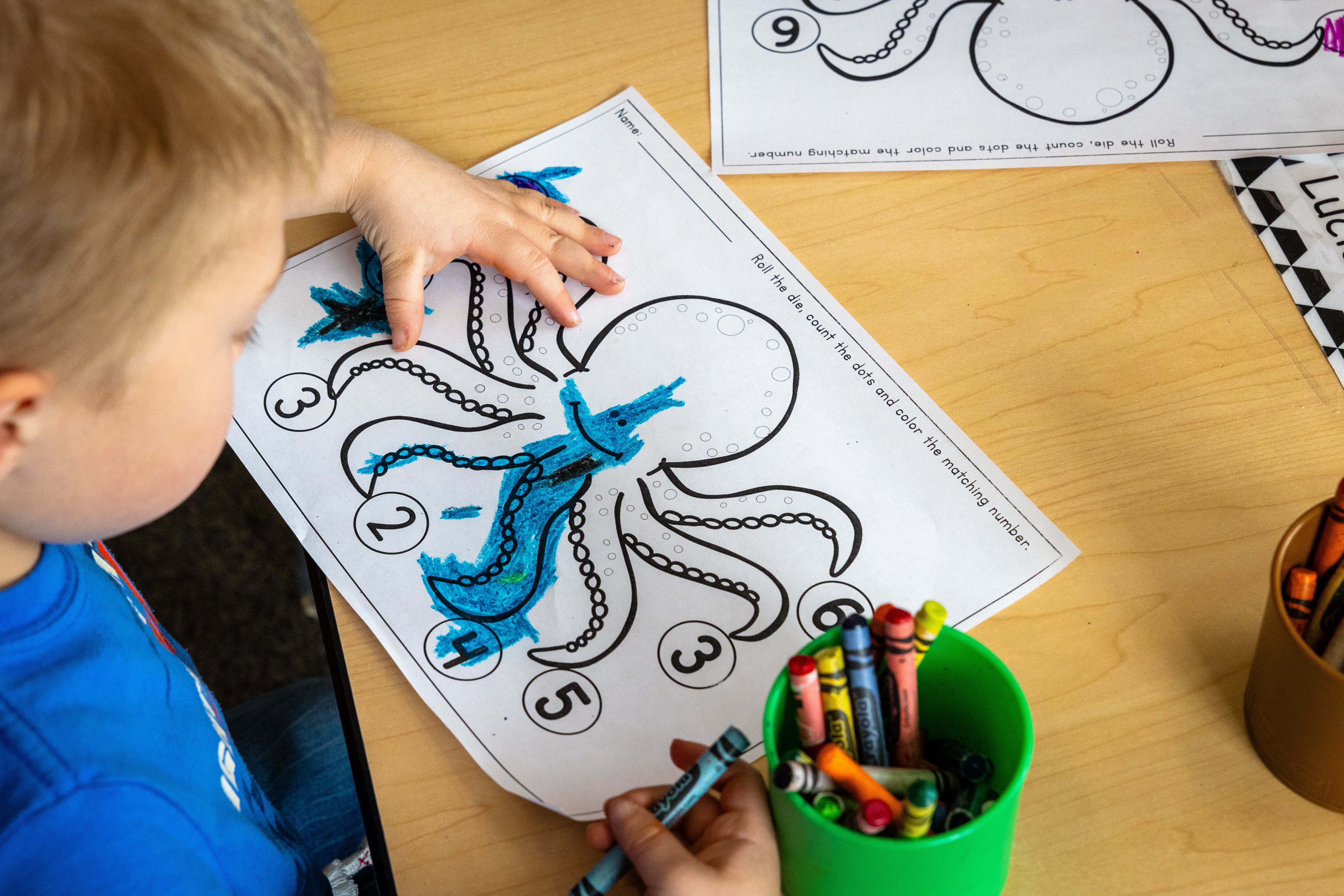 A child colors in an octopus outline with crayons.