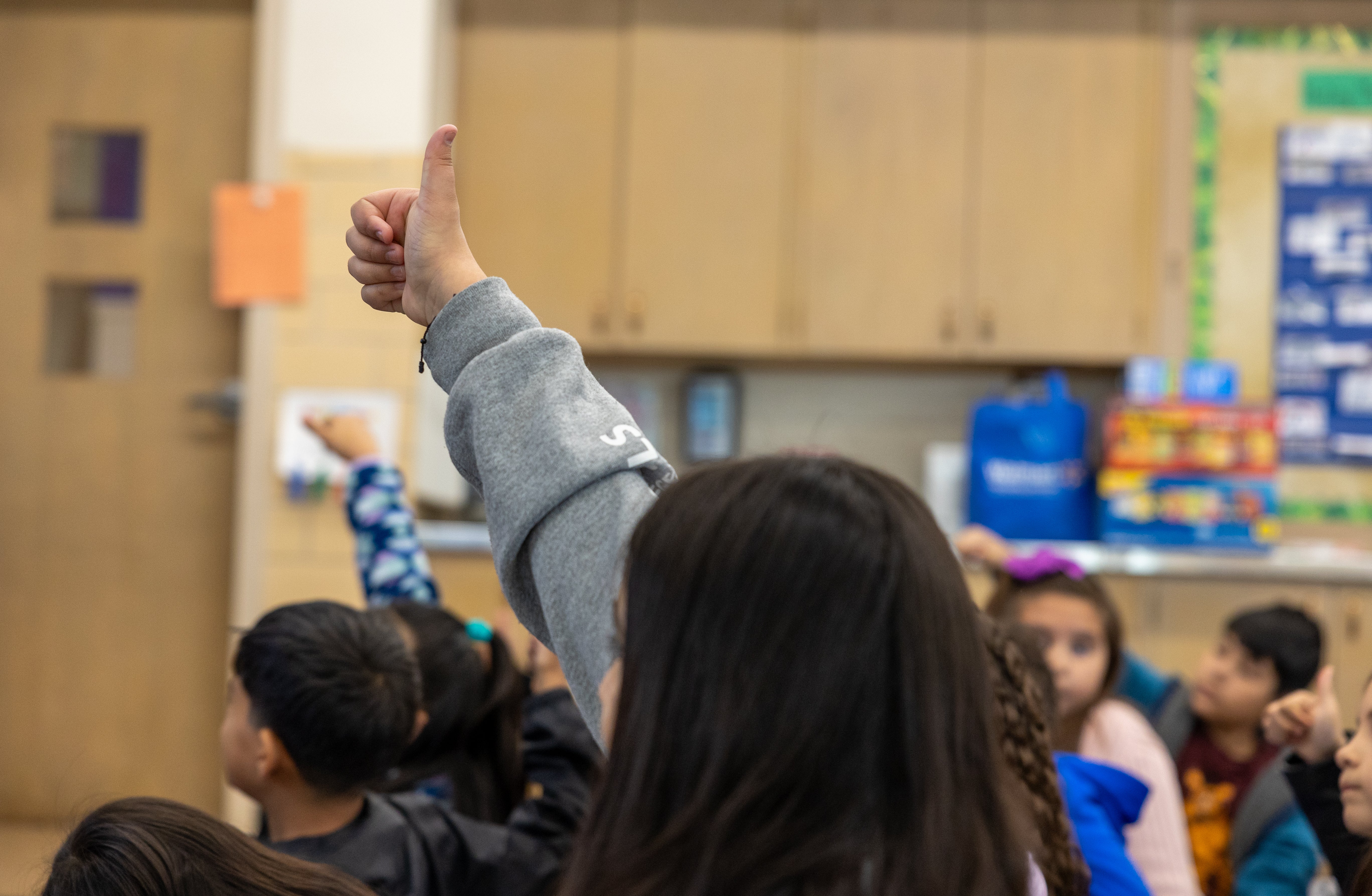 A student puts a thumbs up in the air in response to a question.