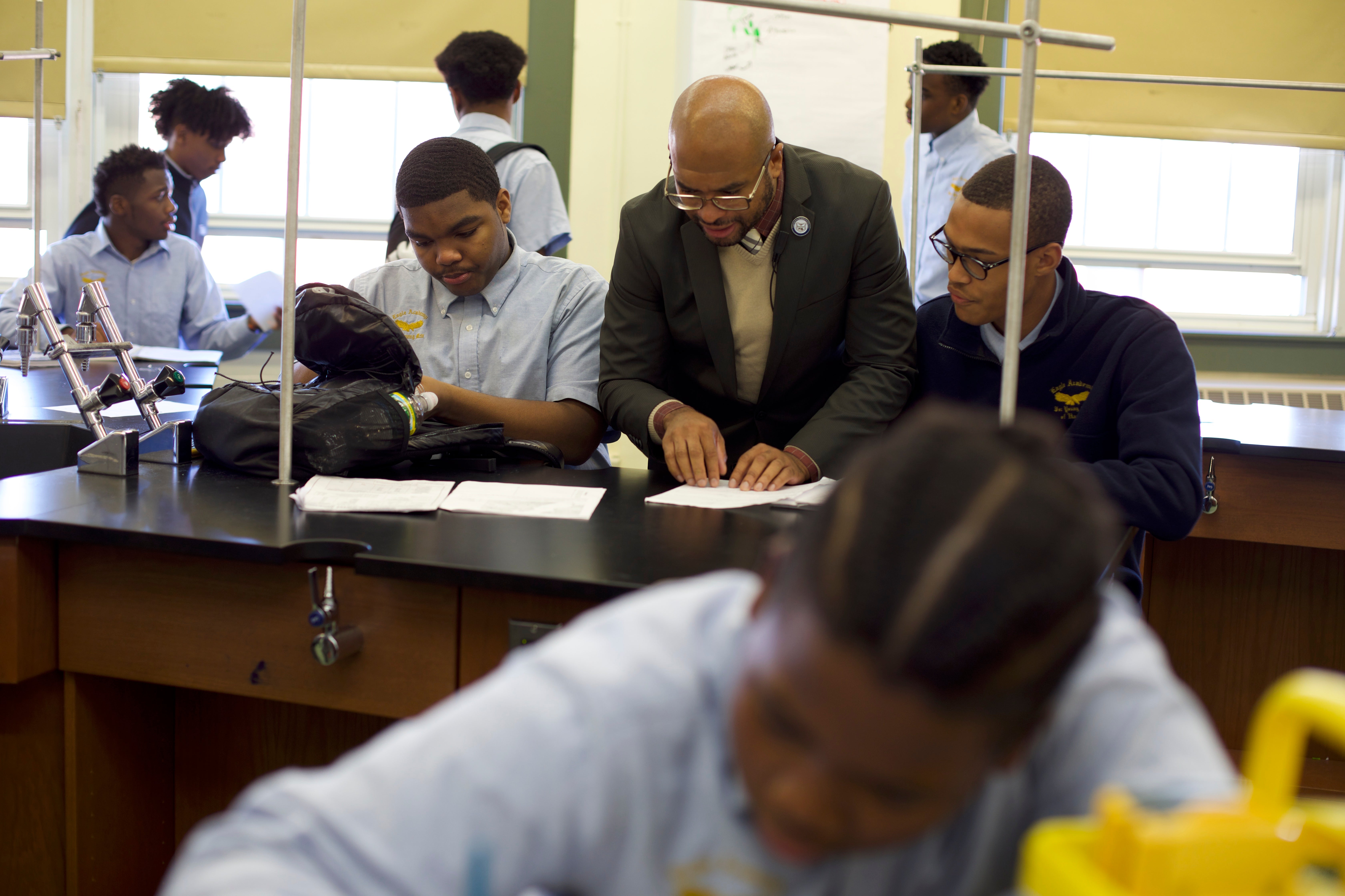 A principal reads an assignment with students during a lab class.