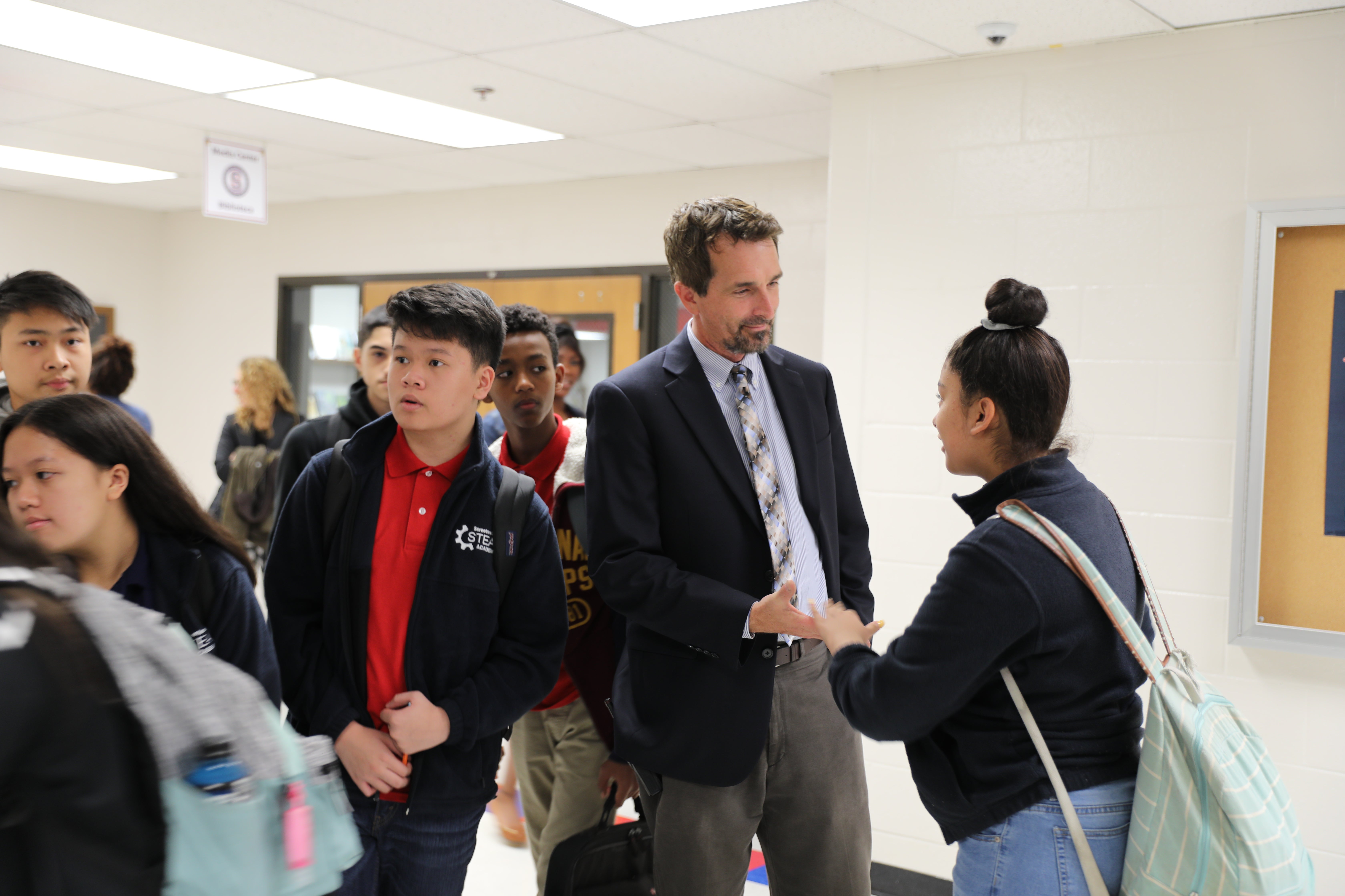 A principal greets a student between classes.