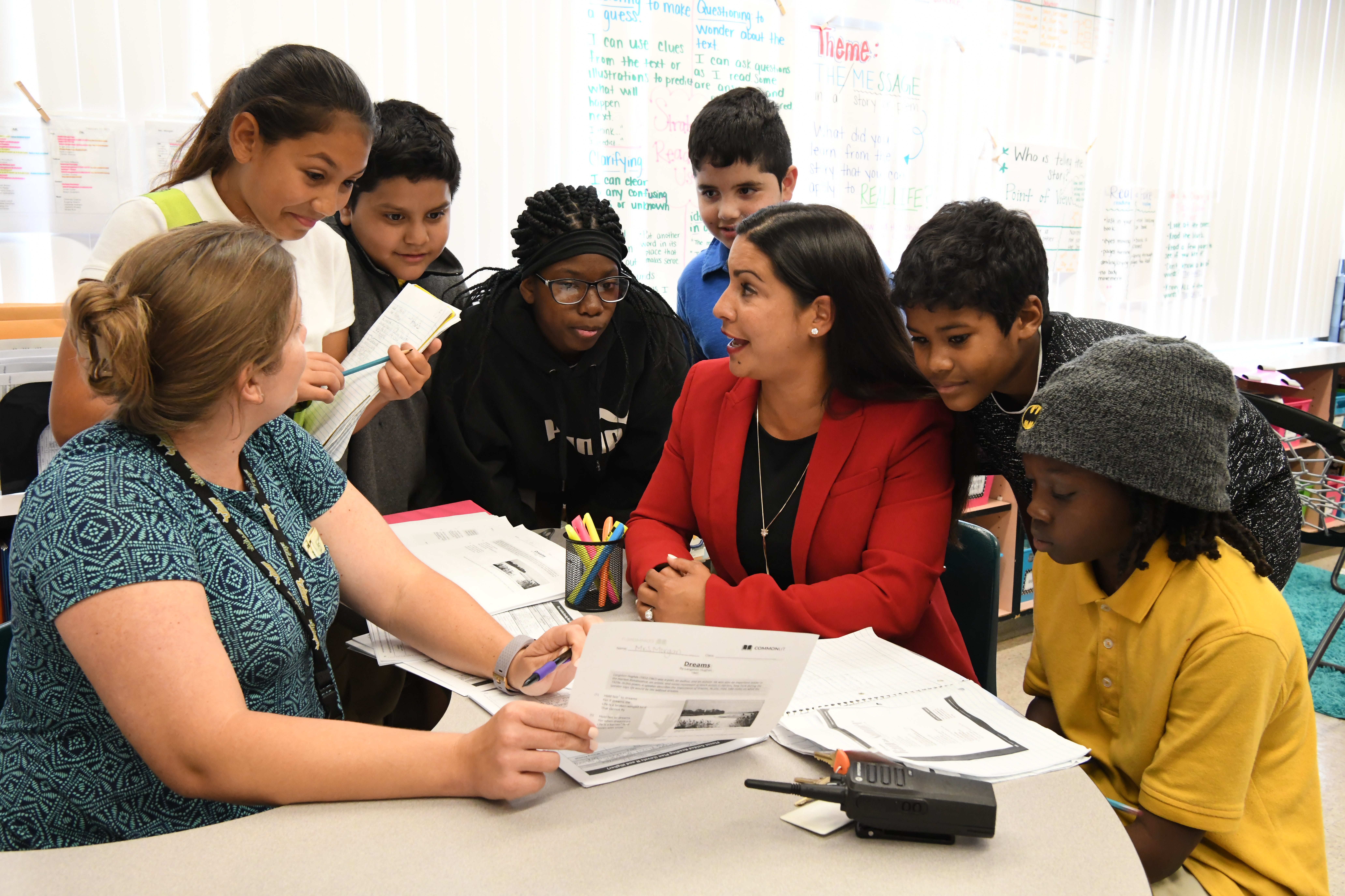 A school principal surrounded by students in a classroom.