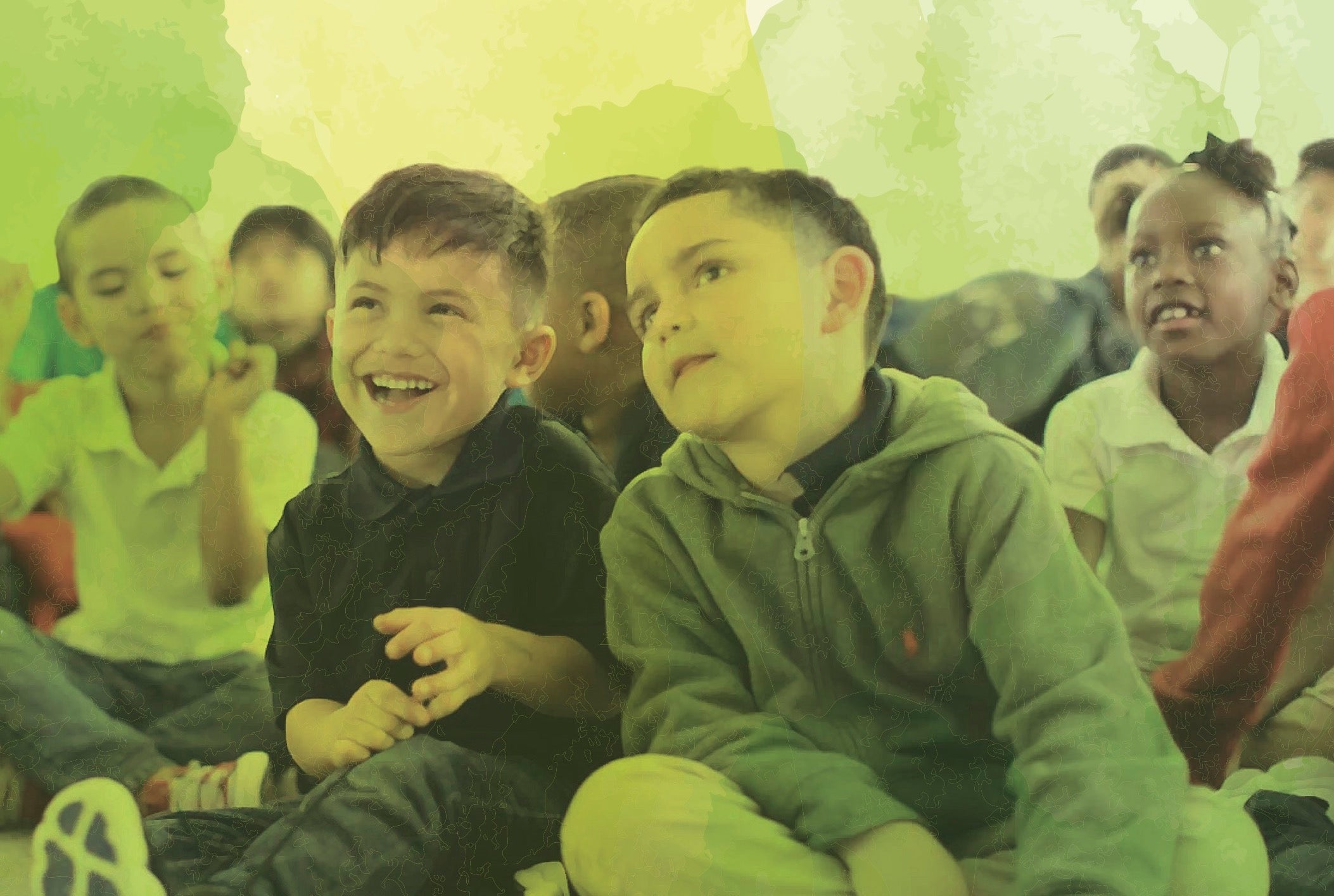 Children sit on the ground during an assembly.