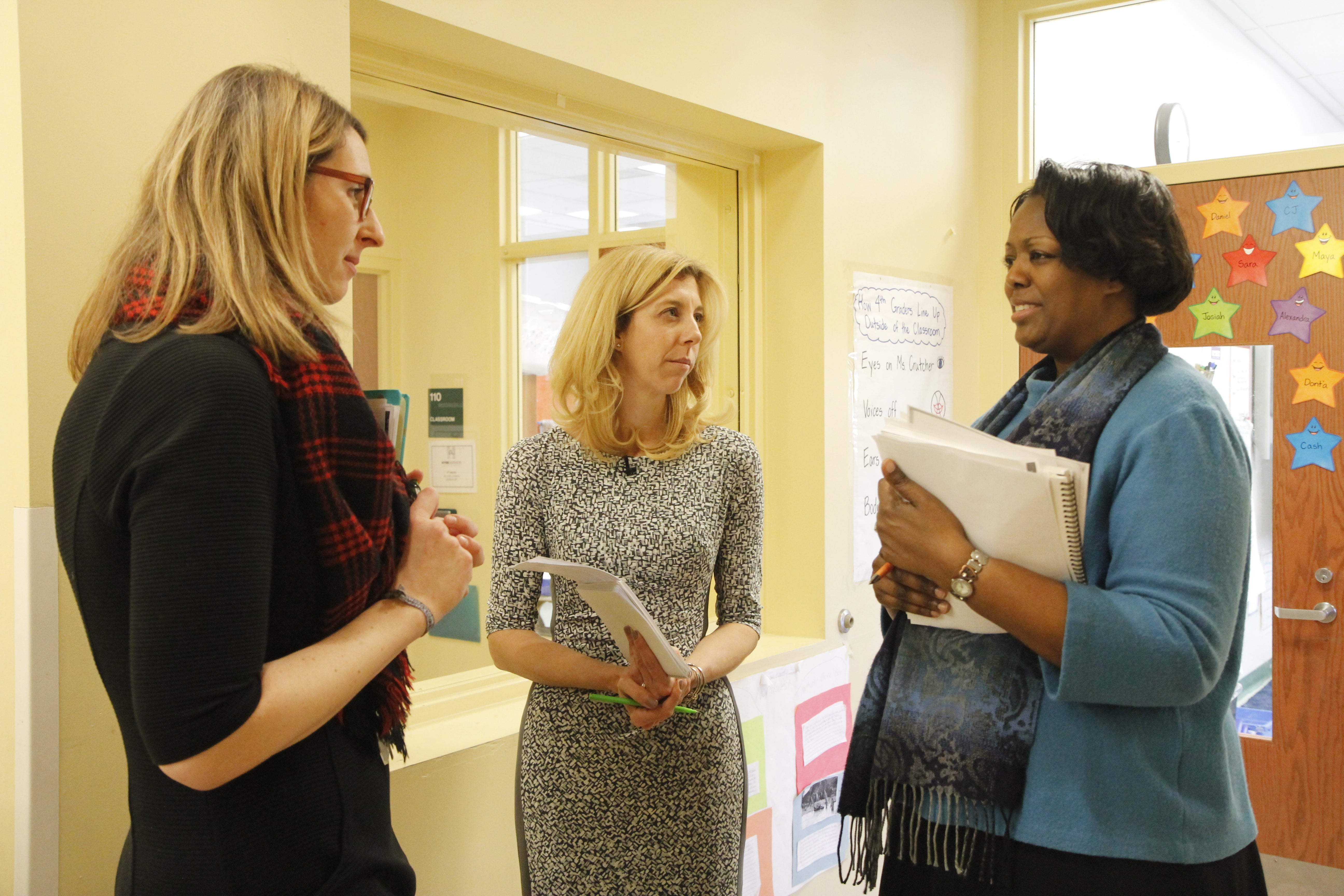 Two teachers chat with an instructional coach.
