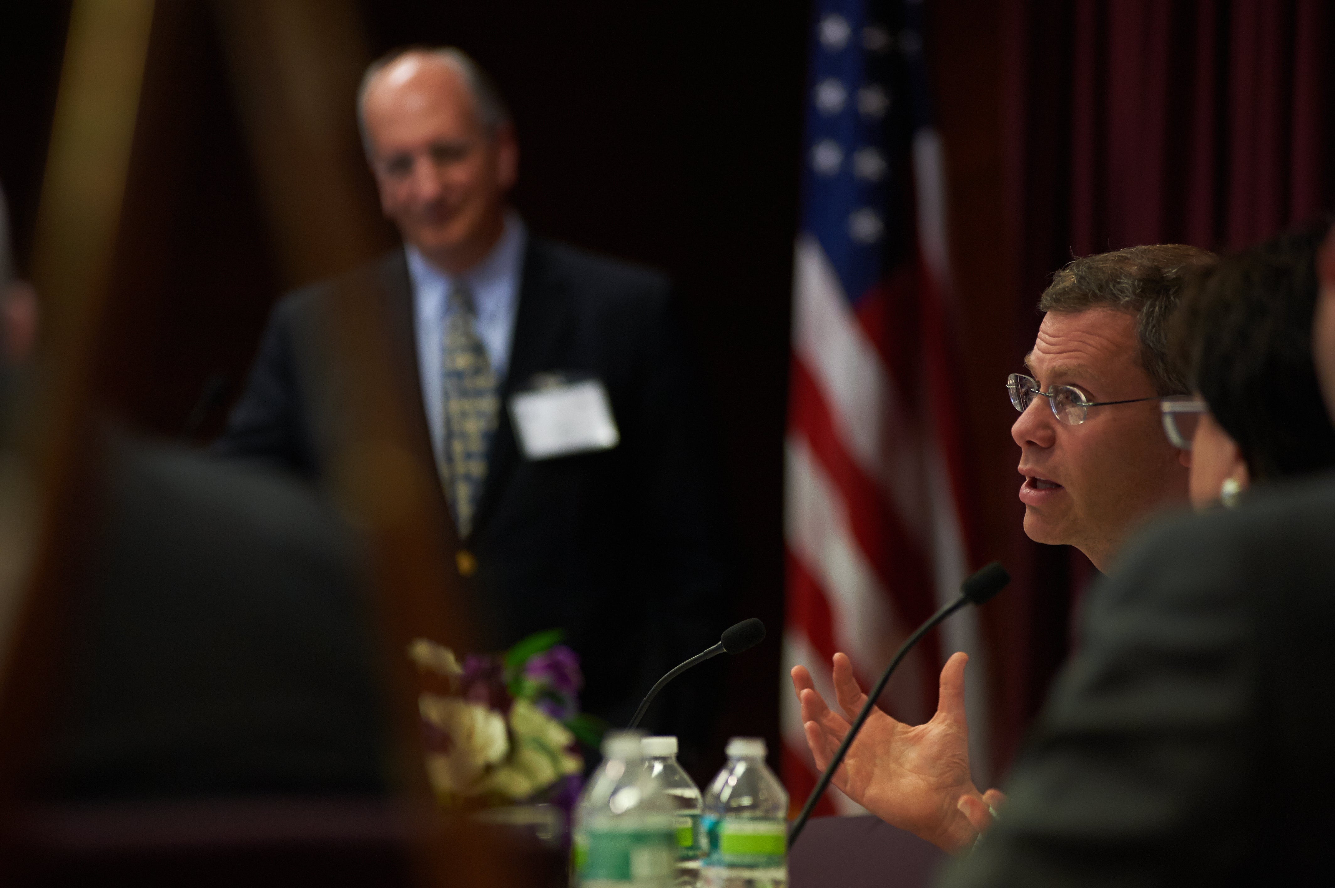 A man speaks into a microphone at a panel during a conference.