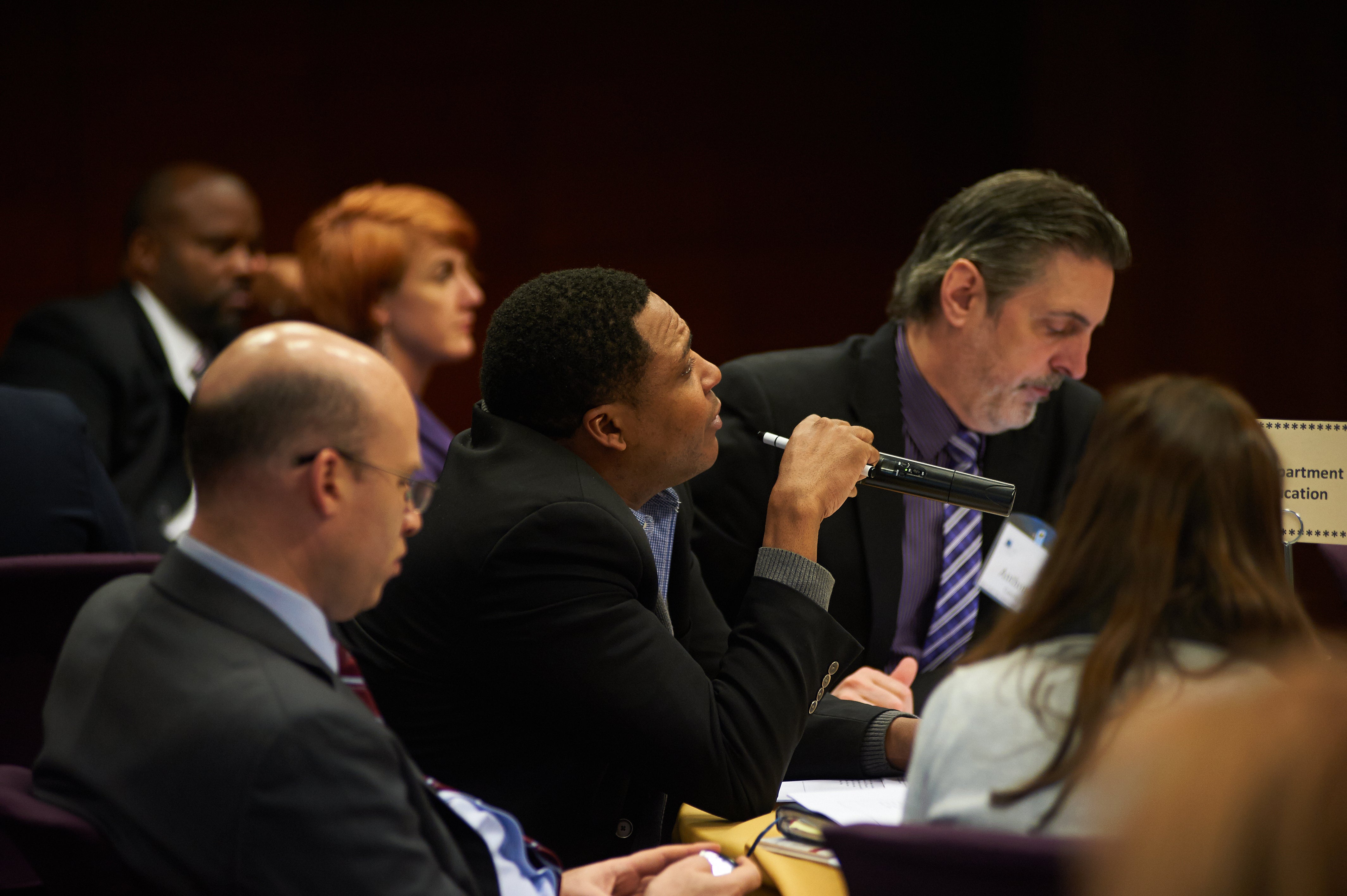 An attendee at an education leadership conference asks a question to the panelists.