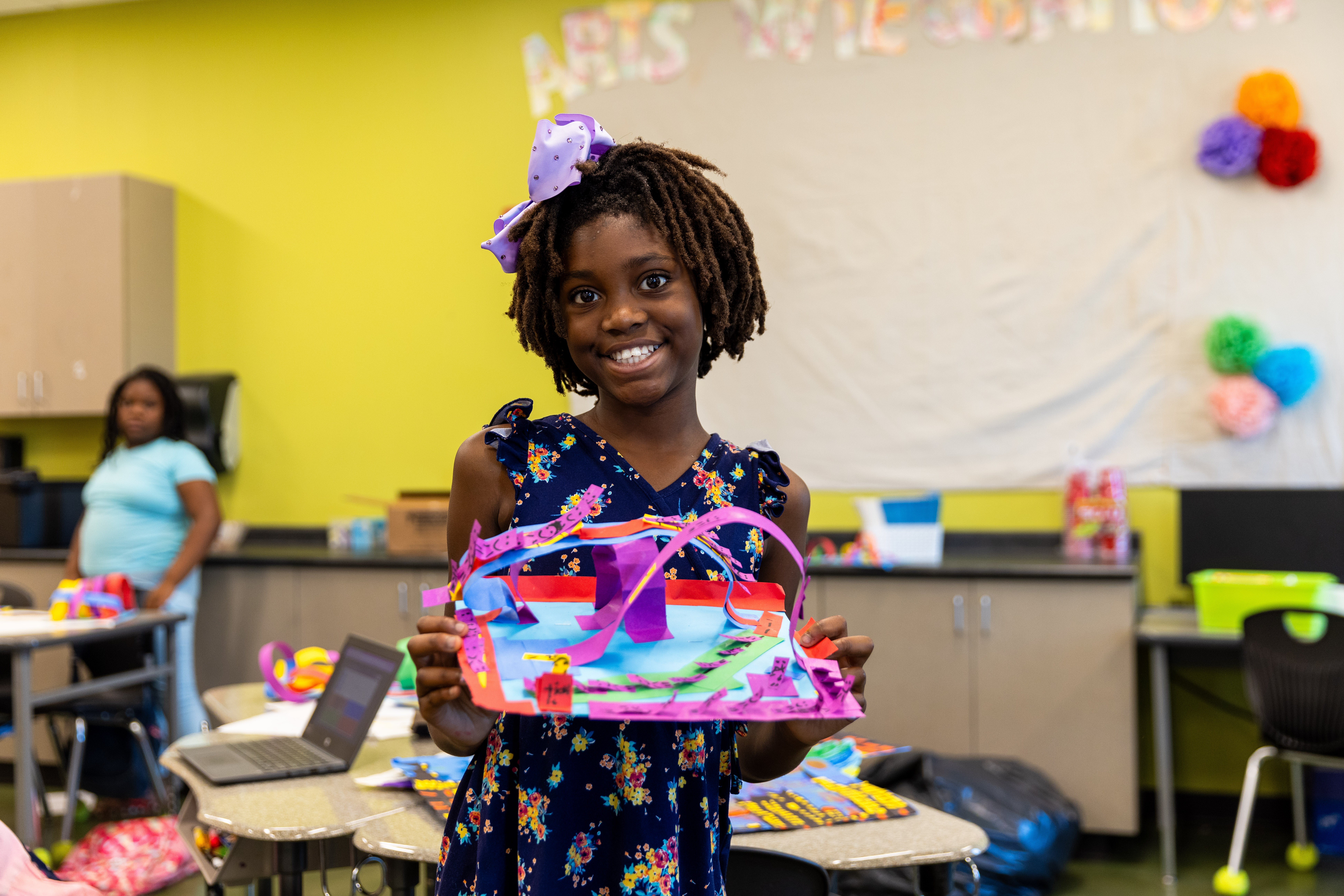 A girl holds up her summer program project.