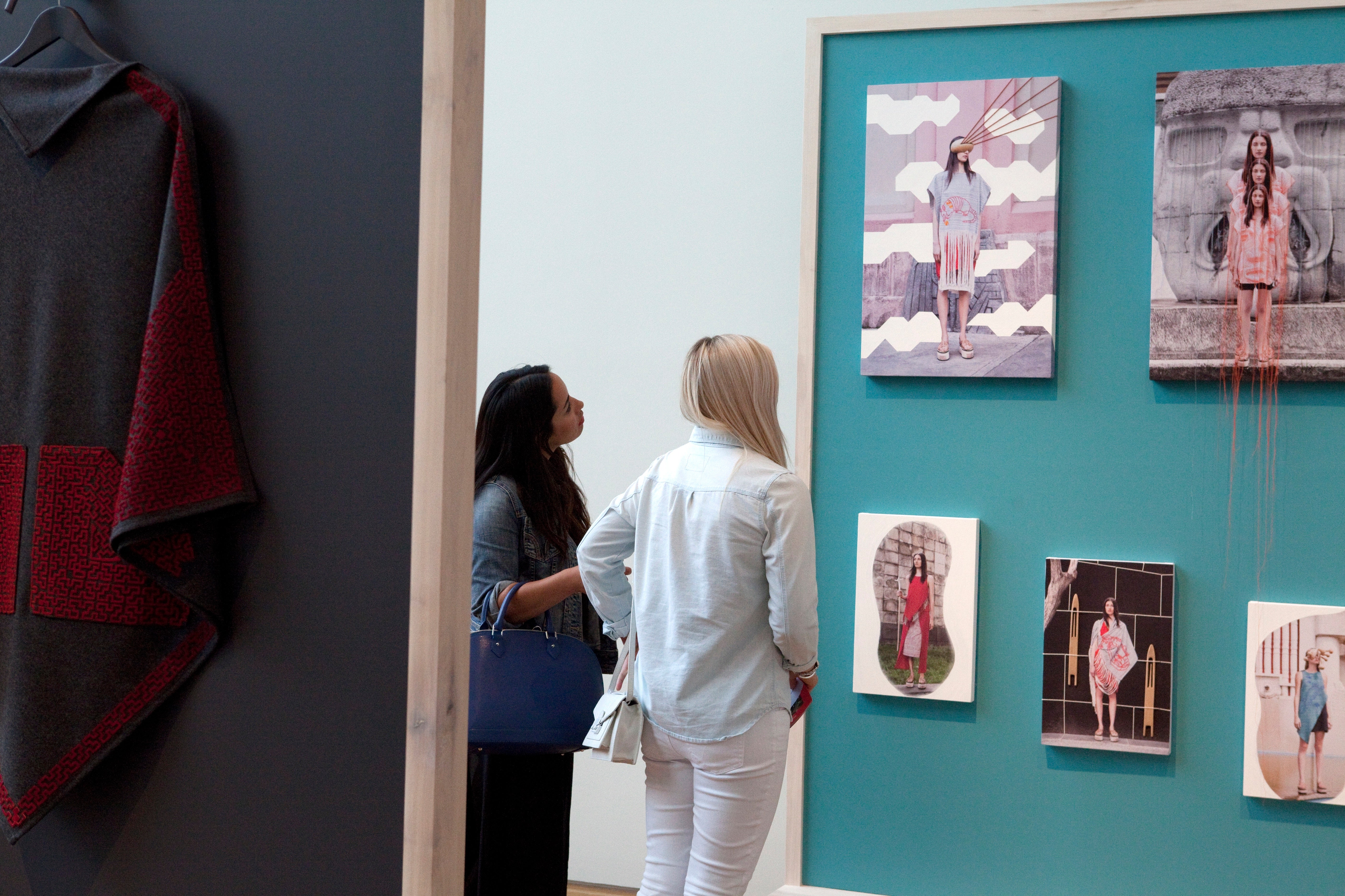 Two attendees look at an art gallery wall.