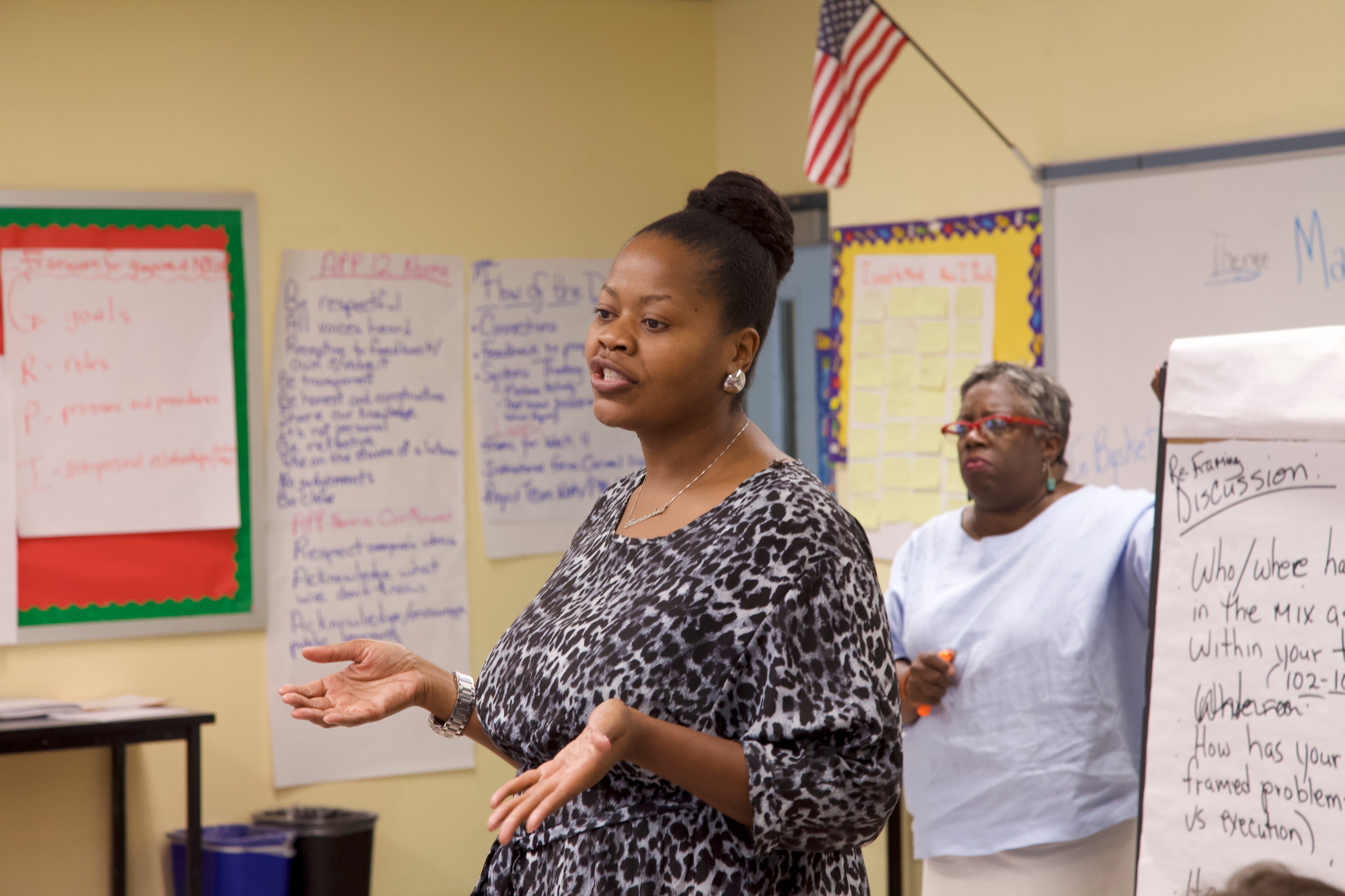 Education leaders engage in discussion in a classroom.