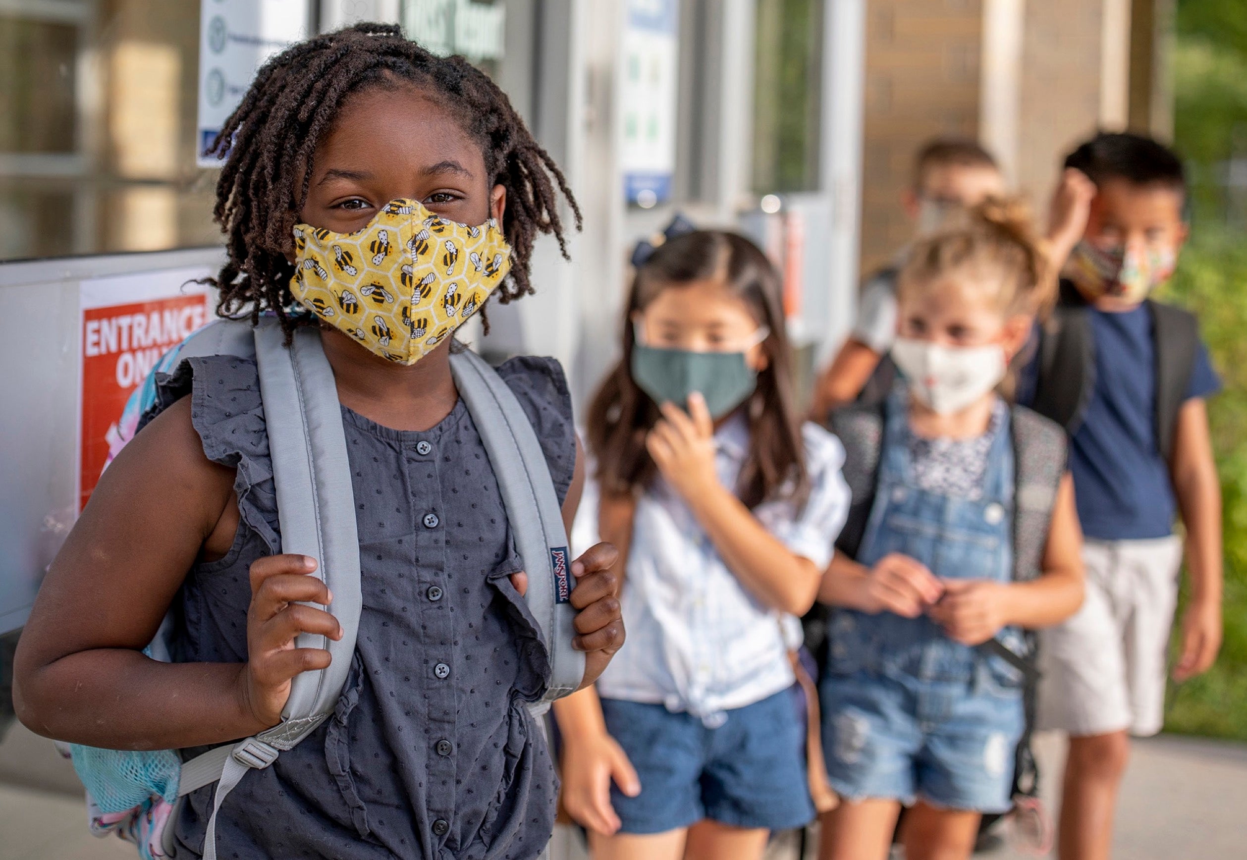 Students in masks line up in a row.