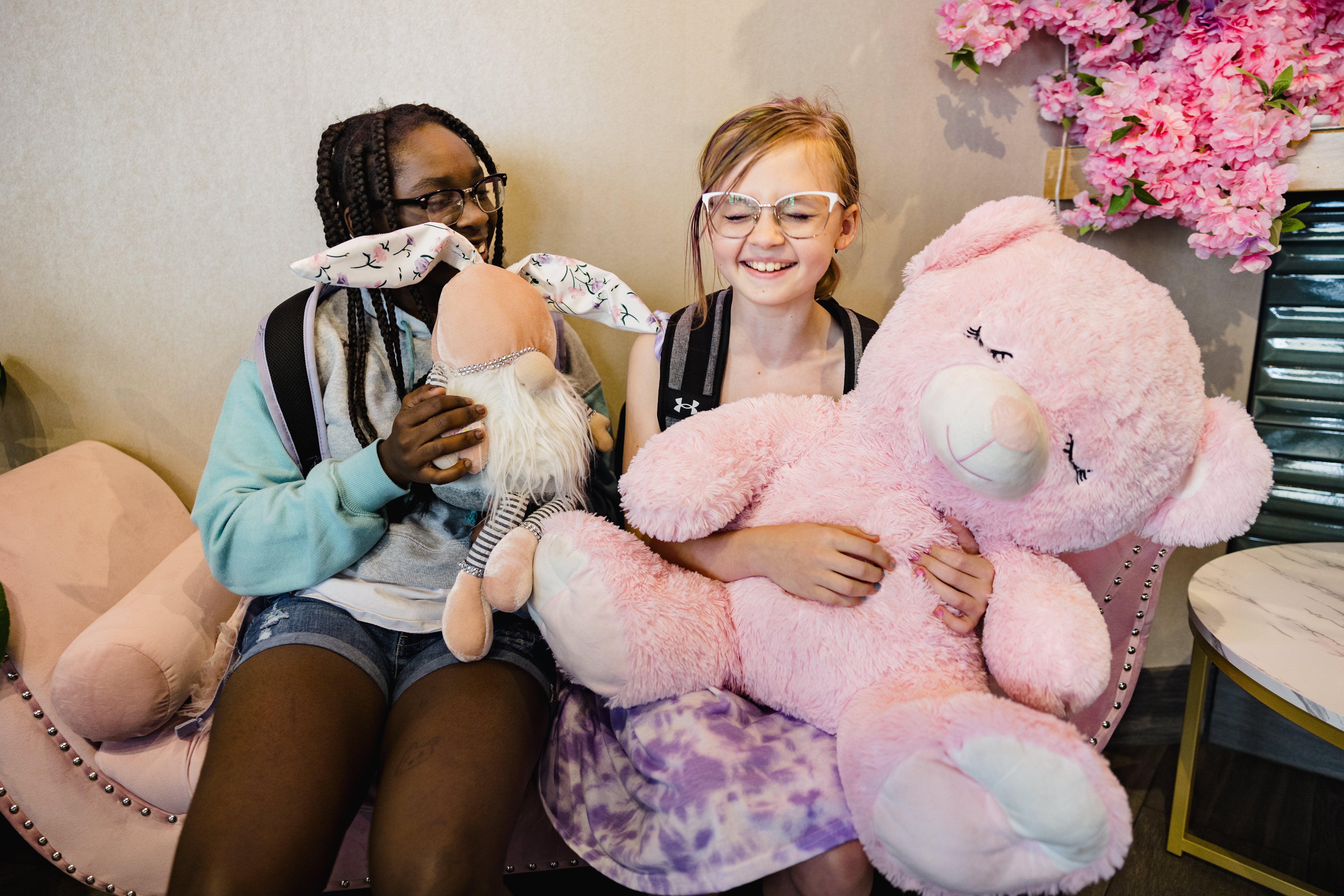 Two girls during summer camp cuddle their stuffed animals.