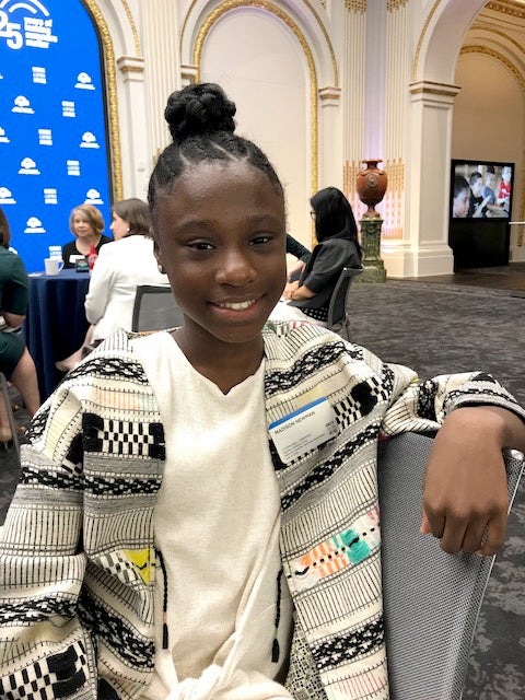 Madison Newman, a student, smiles at the camera while sitting on a chair.