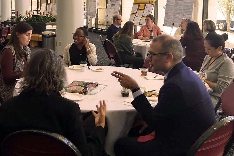 Groups of arts education leaders sit at round tables during a conference.