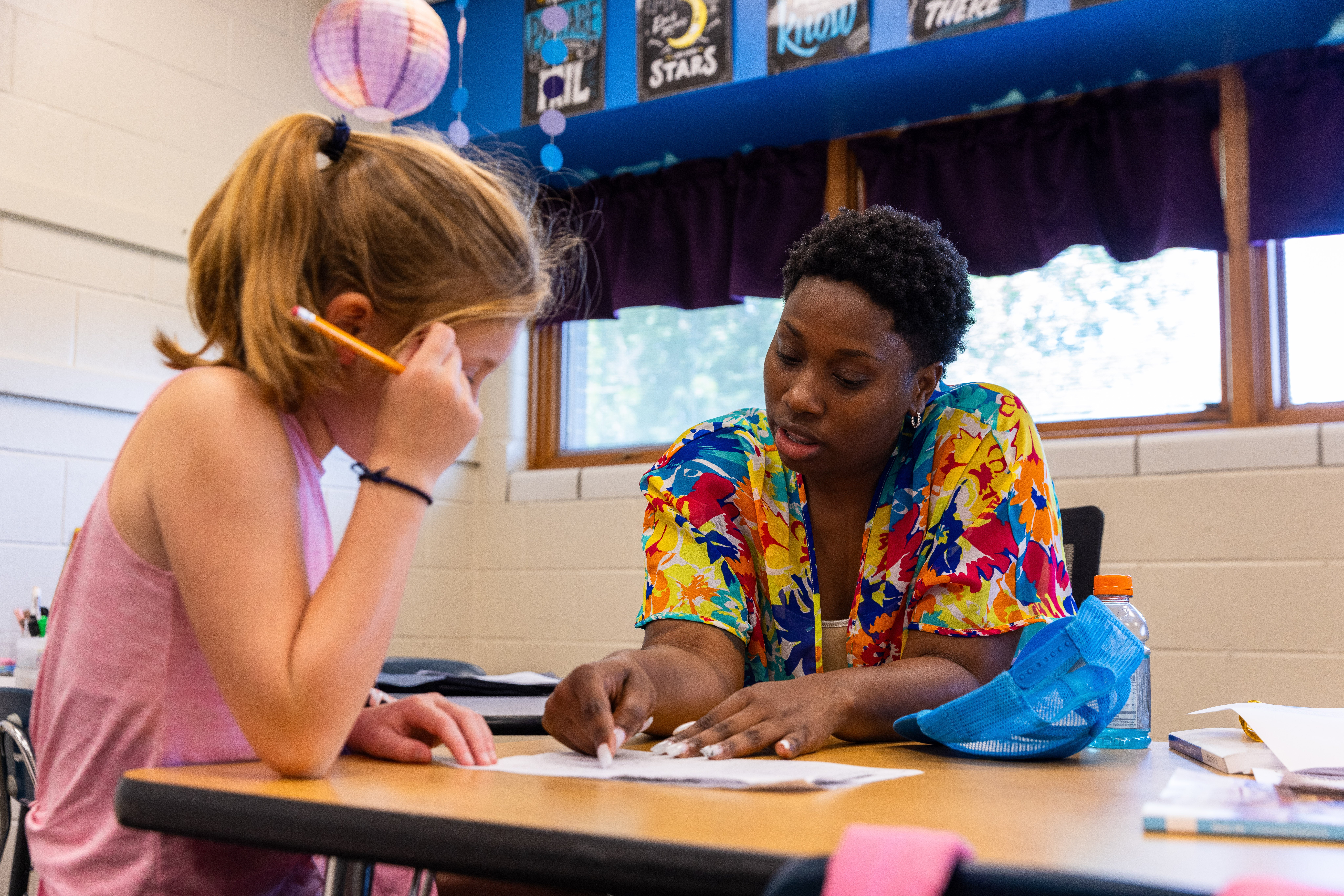 A black teacher helps a white student in the foreground in a classroom at Tuscaloosa School