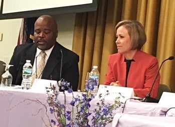 Two education leaders sit at a panel table during a conference.