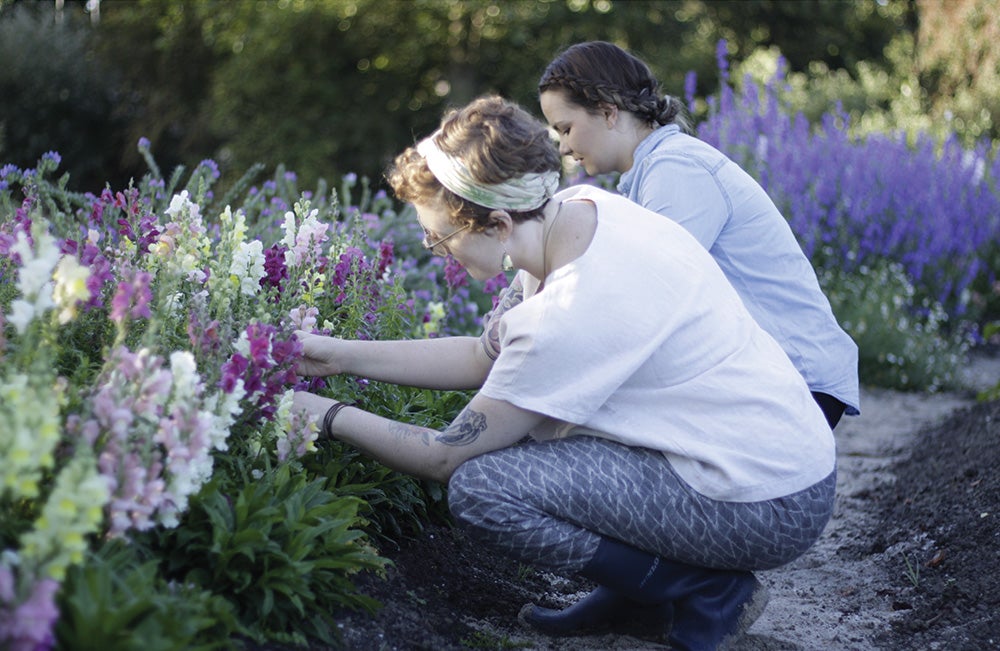 Two women tend to flowers in the garden.