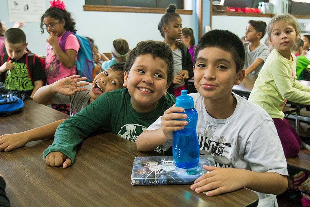 A group of young students at a table hanging out.