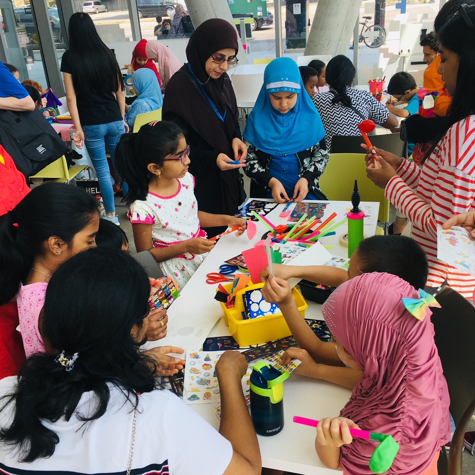 Children and adult helpers gathered around a crafts table.