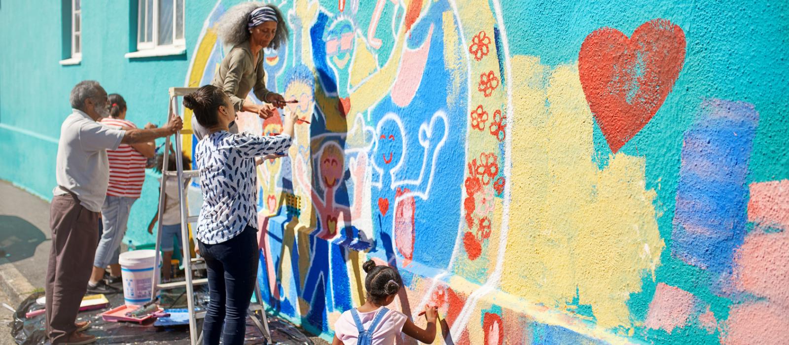 Kids and adults painting a murial