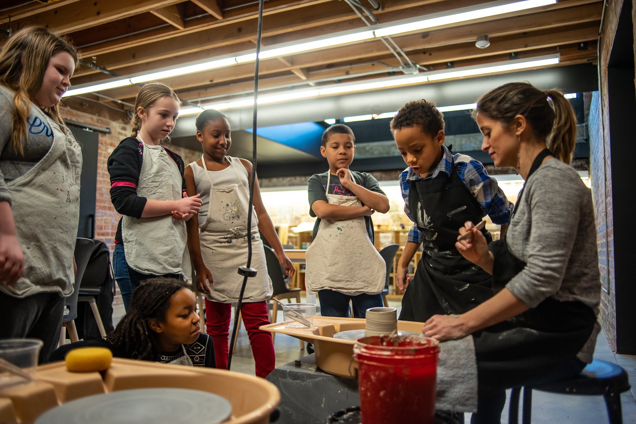 Image of children around a pottery wheel
