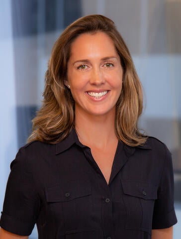 White woman standing in front of a light blue blurred background